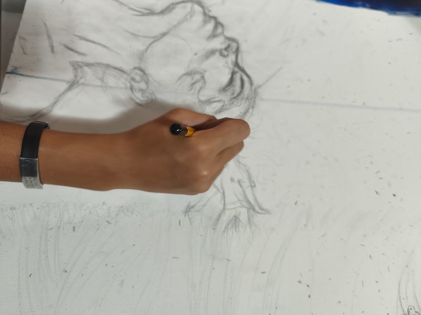 Mão desenhando a lápis o rosto da obra Chama na tela